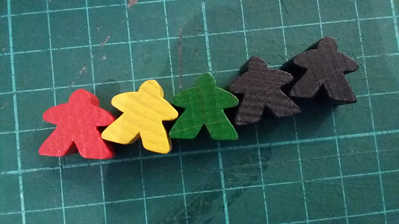 Image showing Carcassonne’s meeples. It looks like I’m about to dissect them on my cutting mat, but I assure you no meeples were harmed in the writing of this article.